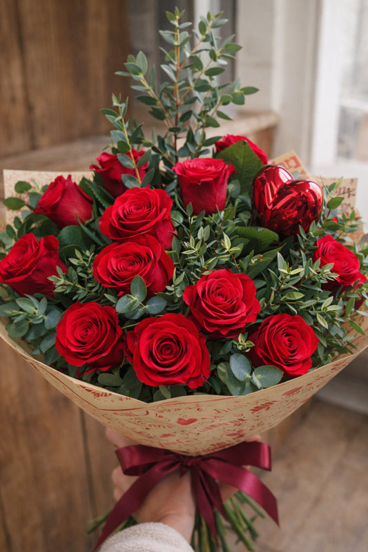 Bouquet of red roses with a red ribbon held by a person.