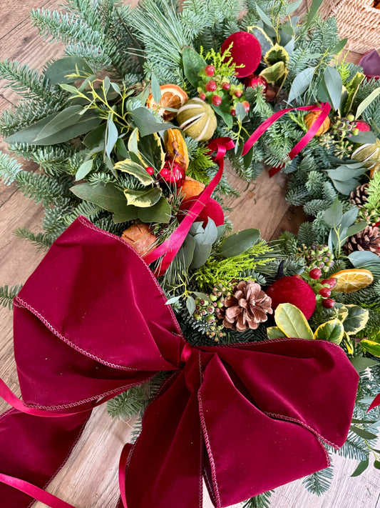 Close-up of The Holiday Wreath with holly, lotus pods, cinnamon, and glass baubles – Barns Florals.