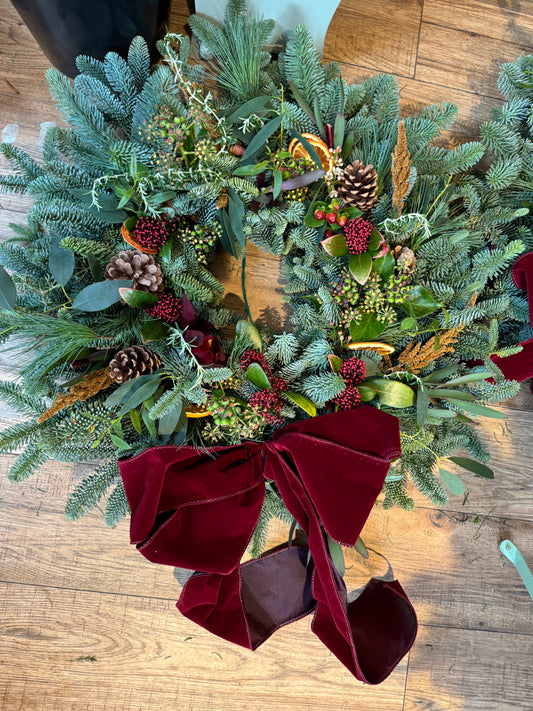 Close-up of Mulled Berries & Wine Wreath showing dried flowers, holly, and lotus pods – Barns Florals.
